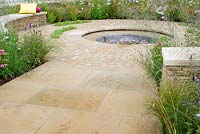 Dry stone walls around circular water feature, stone slab and cobble paths and borders with colourful naturalistic planting in the 'The Mornflake Garden' sponsored by Mornflake Cereals. Gold medal winner and Best Show Garden - RHS Tatton Flower Show 2012