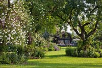A Bavarian country garden with lawn, old fruit trees, climbing roses and perennial borders