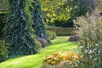 Seat hidden by ivy in border in Autumnal garden
