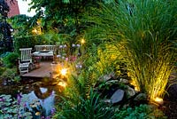 Wooden deck and seating area overlooking pond at dusk