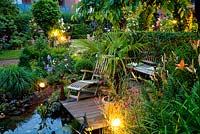 Wooden deck and seating area overlooking pond at dusk