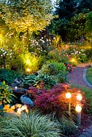 Mixed summer borders with spot lights at dusk 