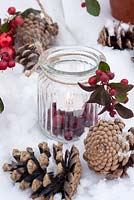 Tealight in glass jar, decorated with berries of Gaulteria procumbens and cones
