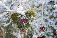 Snowy moss heart with ribbon displayed hanging on branch
