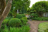 Terrace of terracotta tiles and bricks. Plants include Buxus and Taxus balls and hedges, Apple and Plum trees, Antennaria, Iris - Ulla Molin 