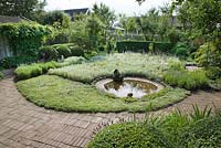 Circular pond surrounded by planting of Lavender, Anaphalis, Antennaria dioica, Apple and Plum trees, Buxus and Taxus topiary and hedges, Artemisia 'Silver queen', Brunnera, Lavender, Veronica spicata with brick and terracotta tile surfaces - Ulla Molin
 