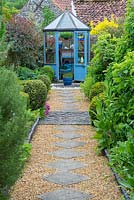 Cottage garden with slab and shingle path leading to hexagonal greenhouse