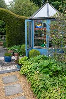 Blue painted, small hexagonal greenhouse in country garden