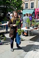 Woman buying fruit bushes at an urban plant sale in Highbury Barn, London Borough of Islington, UK