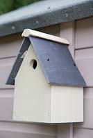 Freshly painted birdbox hanging on shed