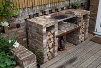 Barbecue with cut logs on decked patio area