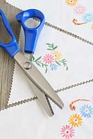 Step by step of making garden bunting with vintage linens and buttons - Using pinking shears, cut out your triangles