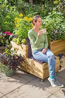 Woman relaxing, drinking tea in small suburban garden