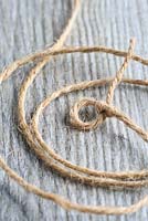 Step by step of making a simple, rustic Christmas garland with fir cones and pine needles - Tie a simple knot in one end of the twine, leaving a small loop for a drawing pin or nail to go through.