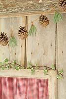 Step by step of making a simple, rustic Christmas garland with fir cones and pine needles - The finished garland hanging on a wooden door