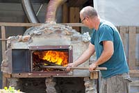 Preparing the pizza oven by burning wood.