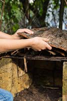 Young girl adding bark for roofing material