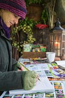 Woman sat in shed garden planning during Winter, for the following year to come.