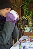 Woman sat in shed garden planning during Winter, for the following year to come.