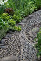 Pebble path designed to stimulate reflexology pressure points. Euphorbia myrsinites in mixed border.  The Get Well Soon Garden 