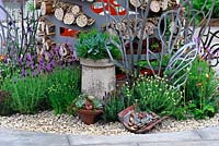 Lavandula, chimney pot with succulents, bee hotels, hole drilled logs and bamboo interplantd with sempervivums