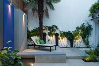 Wall panels with downlights in small urban garden. 