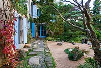 Japanese style garden - view to the east side of the house with blue shutters, path with pebbles and rocks, gravel garden and clipped scots pine