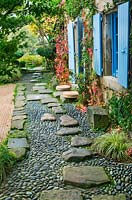 Japanese style garden - view to the east side of the house with blue shutters, path with pebbles and rocks and gravel garden