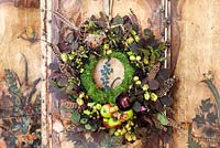 Decorative autumn wreath with feathers hanging on old distressed screen
