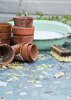 Brush, bowl of bubbly water and collection of dirty terracotta pots ready for cleaning