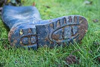 Dirty welly covered in mud, laying on grass lawn