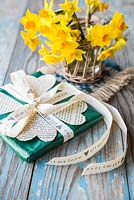 Valentine gift decorated with heart shape cut-outs from a book and a jar of Daffodils. Narcissus