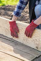 Bending chicken wire to cover scaffold board. 