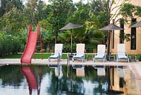 Swimming pool in Moroccan garden with slide and sun loungers