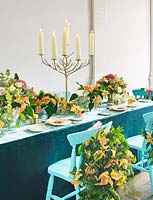 Dining table with blue chairs decorated with candlestick and poinsettia 'Christmas feelings cinnamon' 