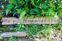 Detail of wooden sign 'We will remember them' with shell casings. The DialAFlight Potter's Garden. RHS Chelsea Flower Show 2014. 
 