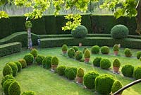Formal garden of clipped evergreens in lawn beside one end of the house. Les Confines, Provence, France