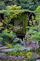 Japanese Garden with Tea house, moongate wall covered in moss and water feature. Togenkyo - A Paradise on Earth. RHS Chelsea Flower Show 2014