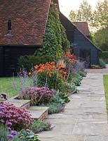 Dahlia border with Dahlia 'Happy Halloween' and 'Spartacus' beneath a vitis coignetiae covered barn 