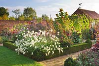 View along brick path with box edged beds - Dahlias, Pennisetum villosum and Helianthus. Ulting Wick, Essex
