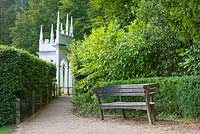 Wooden bench with the exedra in the background. Painswick Rococo Garden, Gloucestershire 