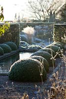Winter garden in frost - the rill garden with canal lined with box balls. 
