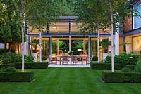 Night view of lawn, glass pavilion, Betula jacquemontii and Hydrangea 'Annabelle' - The Glass House, Petersham - Architects Terry Farrell Partners - Garden design by Sallis Chandler 