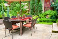 Summer outdoor dining area and patio surrounded by lush gardens. Nandina domestica -Heavenly Bamboo, Taxus baccata 'Fastigiata' - Irish Yew.