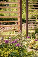 Mixed border planting including Allium 'Purple Sensation', timber sreening and wildflowers beyond, 'Bringing Nature Home', show garden, RHS Malvern Spring Festival 2014