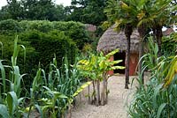 Model garden representing Africa with a mud hut, bananas, palm trees and ornamental grasses. Seend, Wiltshire
