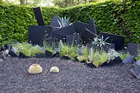 Title: Paradis inverse. Big black ornaments and black slates planted with Agave americana and black rubber on the surface.