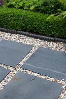 Contrasting textures of 20ml gravel Moonstone with slate natural stone paving in squares before blue rope edging and low Box hedging