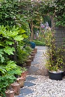 An acrylic mirror on the fence fools the eye into thinking that the garden goes on. Pots and tiles on the ground add to the illusion