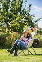 Women sitting in a wheelbarrow within an allotment plot.